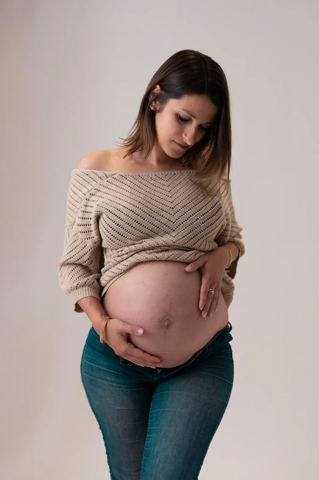 Future maman en jean et pull en maille pour une séance grossesse naturelle