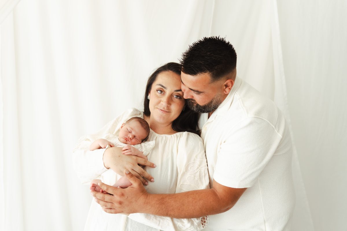 Parents habillés en blanc tenant leur nouveau-né