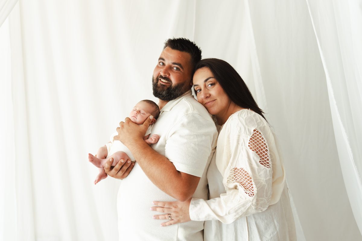 Portrait de famille avec un nouveau-né dans une ambiance blanche