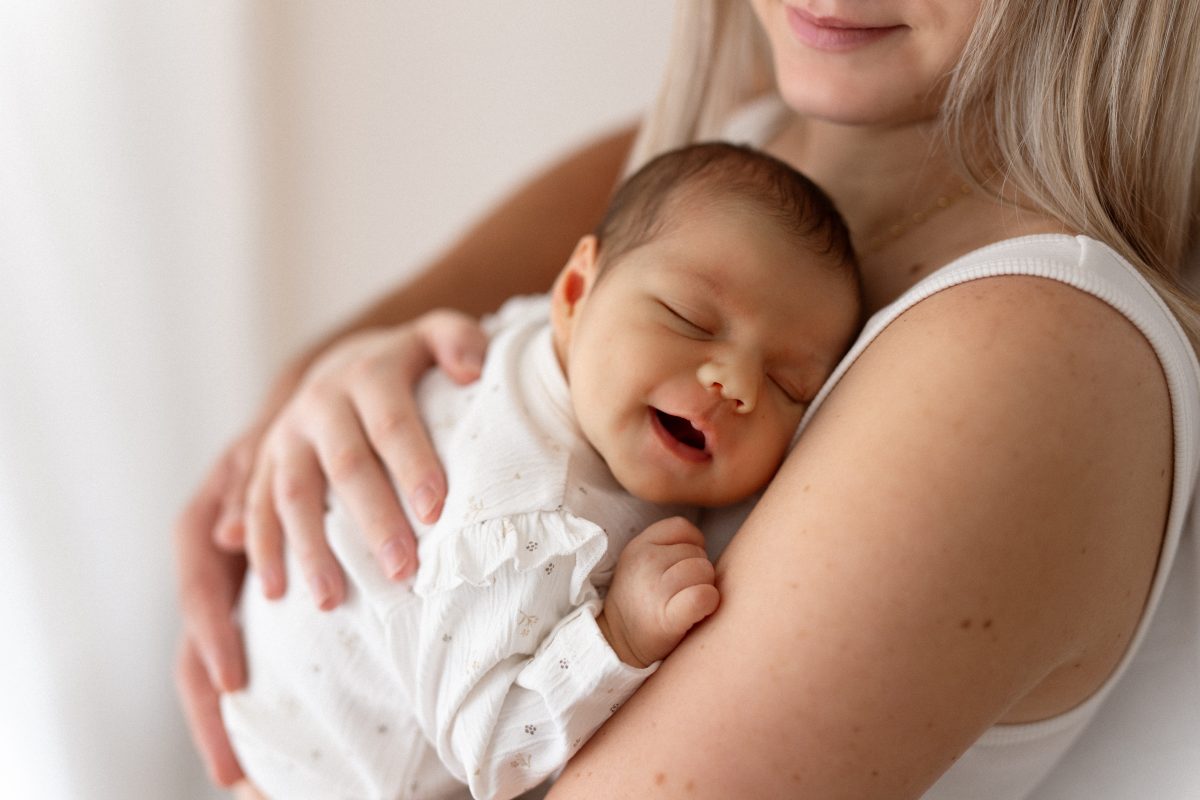 Nouveau-né souriant dans les bras de sa maman