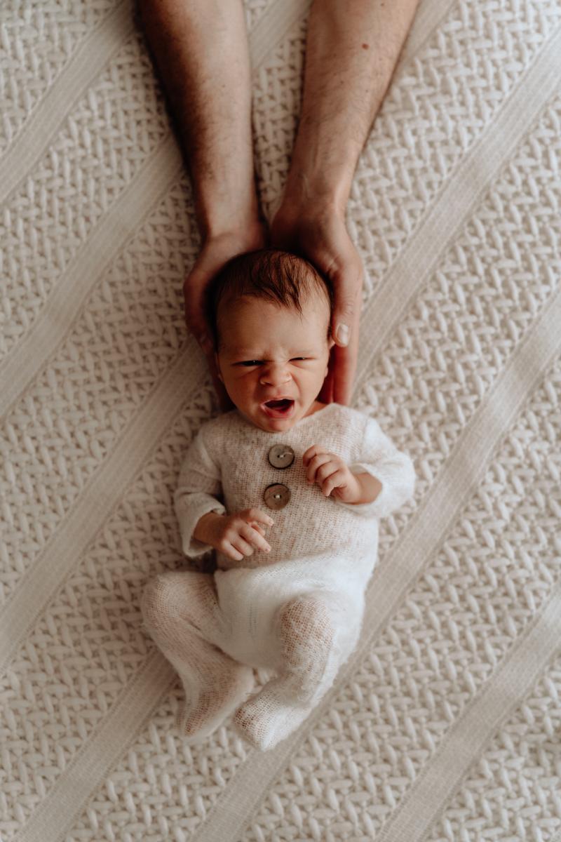 Bébé allongé sur une couverture claire avec une expression spontanée