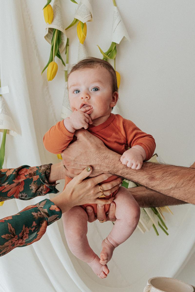 Bébé éveillé tenu par les mains de ses parents